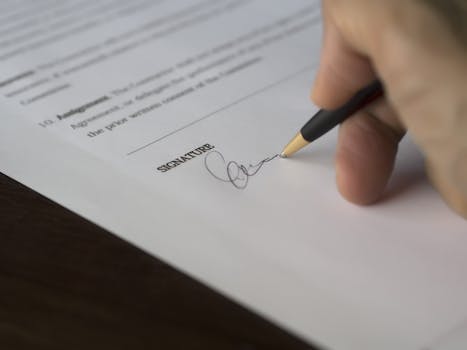 Hand signing a formal contract with a pen